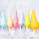 Flat lay. Piping bags with pastel color royal icing to decorate Easter sugar cookies.