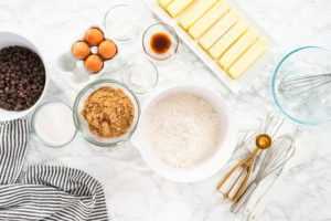 Baking cookies - Arina Photography Flat lay. Mixing ingredients in a glass mixing bowl to bake chocolate chip cookies.