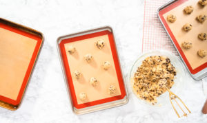 Baking cookies - Arina Photography Flat lay. Homemade chocolate chip cookies dough scoops on a baking sheet with a silicone mat.