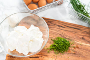 Fresh chopped dill and sour cream on a wood board, prepared for dipping sauce.