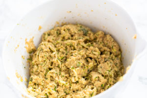 Fully mixed zucchini dough in a white mixing bowl, ready to shape into patties.