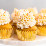 Pumpkin spice cupcake with Italian buttercream and sprinkles on a cake stand.