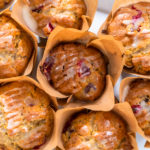 Freshly baked cranberry muffins in brown paper muffin cups.