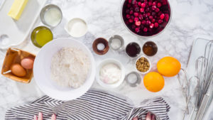 Flat lay. Step by step. Ingredients to bake cranberry muffins on a marble kitchen surface.