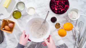 Flat lay. Step by step. Mixing ingredients in a mixing bowl to bake cranberry muffins.