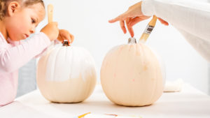 Step by step. Mother and daughter decorating Halloween craft pumpkin with unicorn theme.