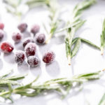 Covering fresh cranberries and rosemary in sugar to decorate chocolate bundt cake with chocolate frosting.