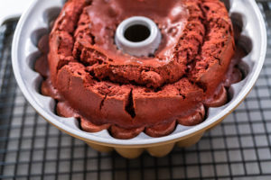 Red velvet cake cooling in bundt pan on wire rack