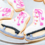 Decorating sugar cookies shaped as figure skates with royal icing.