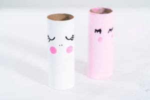 Single white unicorn roll with pink blush and black lashes drying on a white background.