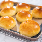 Freshly baked brioche buns on a baking sheet with a silicone mat.