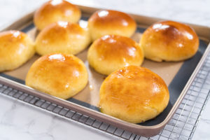 Baking brioche buns - Arina Photography Freshly baked brioche buns on a baking sheet with a silicone mat.
