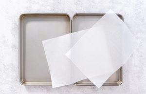 Cooking bacon strips - Arina Photography Two empty baking trays topped with sheets of pre-cut parchment paper.