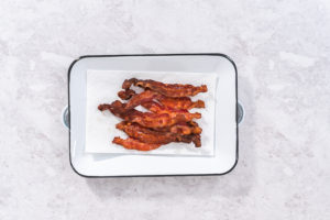 Cooking bacon strips - Arina Photography Fully baked crispy bacon arranged on a clean tray for serving.