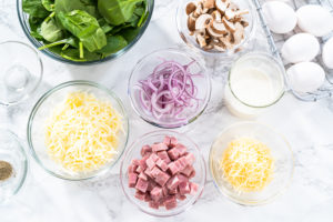 Spinach and ham frittata - Arina Photography All ingredients for spinach and ham frittata laid out in individual glass bowls on white surface.