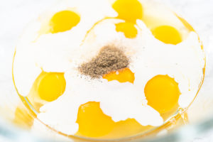 Spinach and ham frittata - Arina Photography Raw eggs and cream with salt and pepper in a glass bowl, ready to be mixed.
