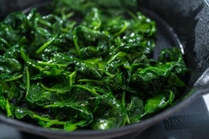 Spinach and ham frittata - Arina Photography Fresh baby spinach cooking down in a frying pan with olive oil.