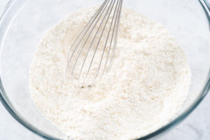 Dry ingredients like flour and baking powder being whisked in a bowl