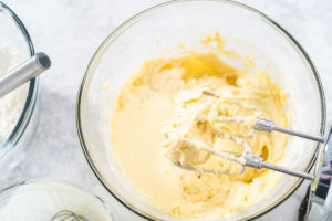 Creamy yellow Bundt cake batter in a mixing bowl with electric beaters after combining wet and dry ingredients.