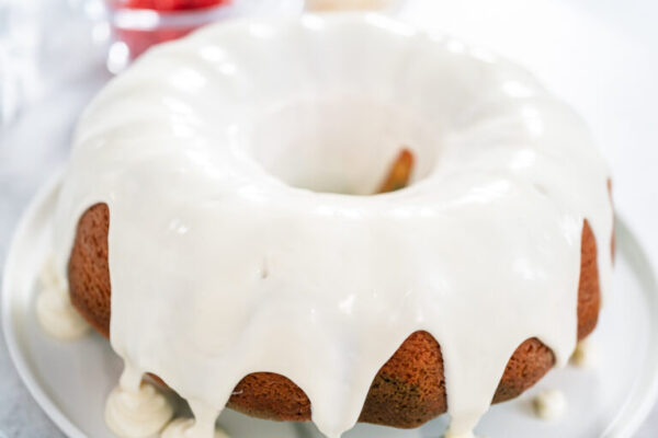 Vanilla-glazed Bundt cake with smooth, even drips cascading down the golden brown edges.