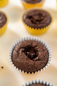Close-up of a chocolate cupcake with a gooey ganache center, nestled in a yellow foil liner, ready to be topped with fluffy marshmallow frosting.