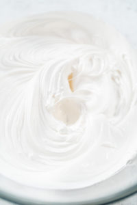 Close-up of smooth, glossy marshmallow meringue frosting whipped to stiff peaks, ready to be piped onto cupcakes.