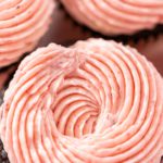 Extreme close-up of a chocolate cupcake topped with a perfect swirl of strawberry frosting.