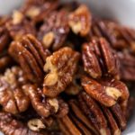 Freshly toasted pecans in a small white bowl.
