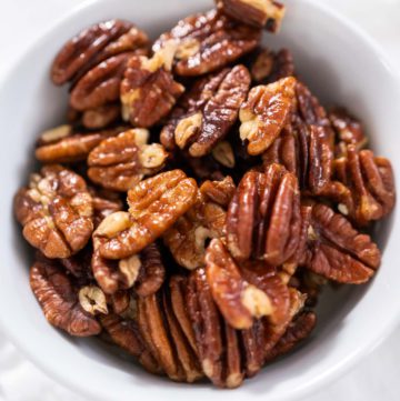 Toasted pecans - Arina Photography Freshly toasted pecans in a small white bowl.