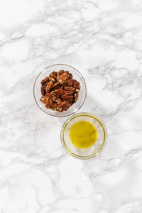Measured ingredients in a glass mixing bowl to make toasted pecans.