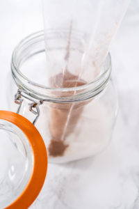 Preparing cinnamon sugar in a glass mason jar.