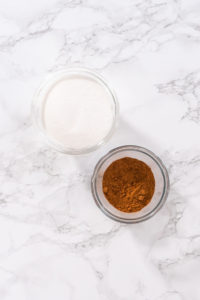 Flat lay. Measured ingredients to prepare homemade cinnamon sugar in small glass bowls.