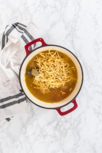 Flat lay. Cooking chicken noodle soup with kluski noodles in an enameled dutch oven.