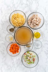 Flat lay. Measured ingredients in glass mixing bowls to make chicken noodle soup with kluski noodles.