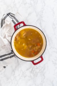 Flat lay. Cooking chicken noodle soup with kluski noodles in an enameled dutch oven.