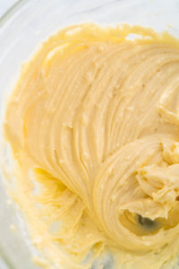 Mixing ingredients in a large glass mixing bowl to make the cream cheese filling for bundt cake.