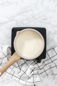 Flat lay. Heating whipped cream in a saucepan to make the white chocolate ganache frosting.