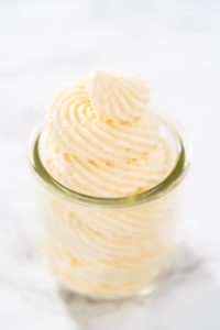 White chocolate ganache frosting in a small glass mason jar.