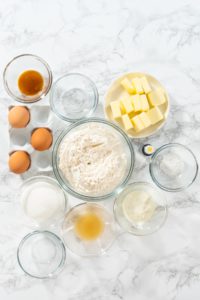 Lemon Wedge Cookies - Arina Photography All ingredients for lemon cookies displayed in glass bowls: butter, flour, sugar, lemon juice, eggs, vanilla, extract, yogurt, and food coloring.