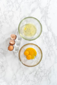 Lemon Wedge Cookies - Arina Photography Eggs separated with shells beside two bowls on marble surface.