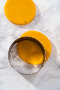 Lemon Wedge Cookies - Arina Photography Rolled cookie dough with round cookie shapes cut out.