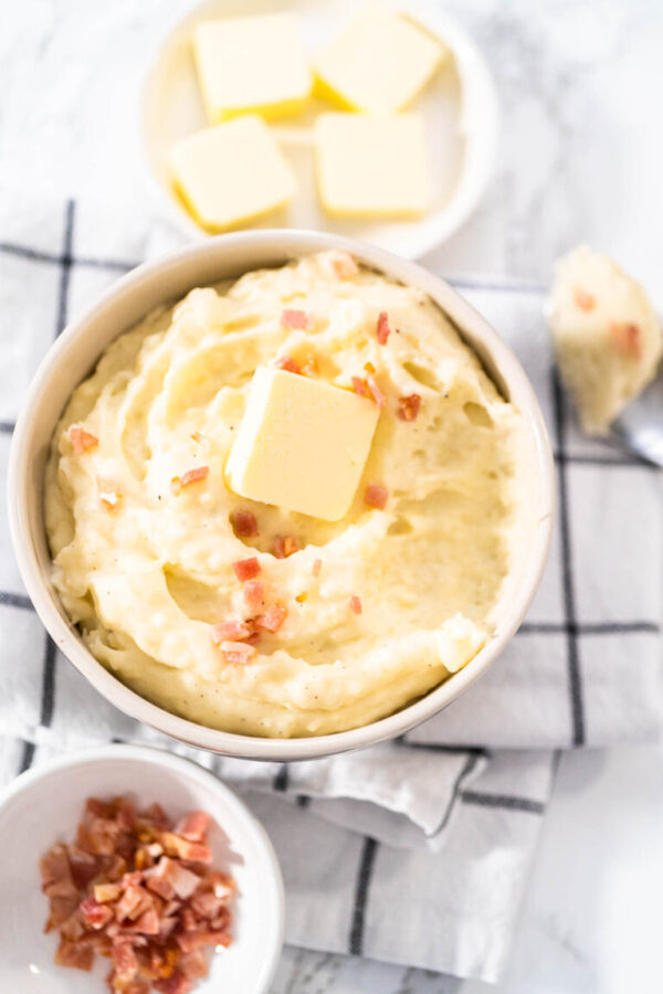 Mashed potatoes. Creamy mashed potatoes garnished with a slice of butter and bacon bits in a bowl.