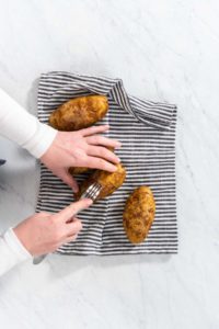 Pressure Cooker Baked Potatoes - Arina Photography Flat lay. Pressure Cooker Baked Potatoes. Poking raw potatoes with a fork to prepare baked potatoes.