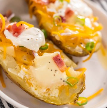 Pressure Cooker Baked Potatoes - Arina Photography Pressure Cooker Baked Potatoes. Garnished large baked potatoes with butter, sour cream, cheese, and bacon bits on a white plate.