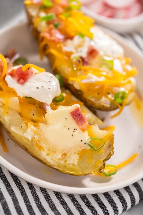 Pressure Cooker Baked Potatoes - Arina Photography Pressure Cooker Baked Potatoes. Garnished large baked potatoes with butter, sour cream, cheese, and bacon bits on a white plate.