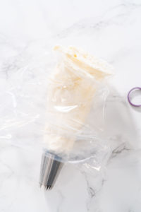 Lemon Buttercream - Arina Photography Filled piping bag twisted and sealed, ready to frost cupcakes.