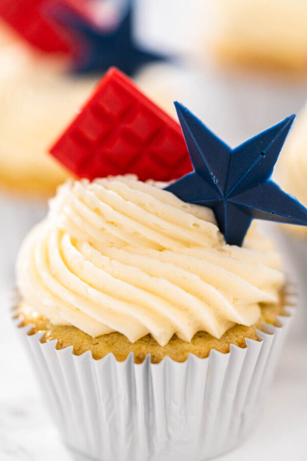 Frosted cupcake with red chocolate square and blue chocolate star topper.