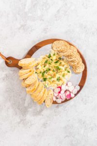 Butter board with vegetables and bread - Arina Photography Flat lay. Assembling butter board with vegetables and bread on a round wood cutting board.