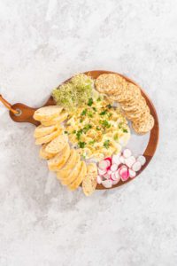 Butter board with vegetables and bread - Arina Photography Flat lay. Assembling butter board with vegetables and bread on a round wood cutting board.