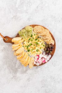 Butter board with vegetables and bread - Arina Photography Flat lay. Assembling butter board with vegetables and bread on a round wood cutting board.